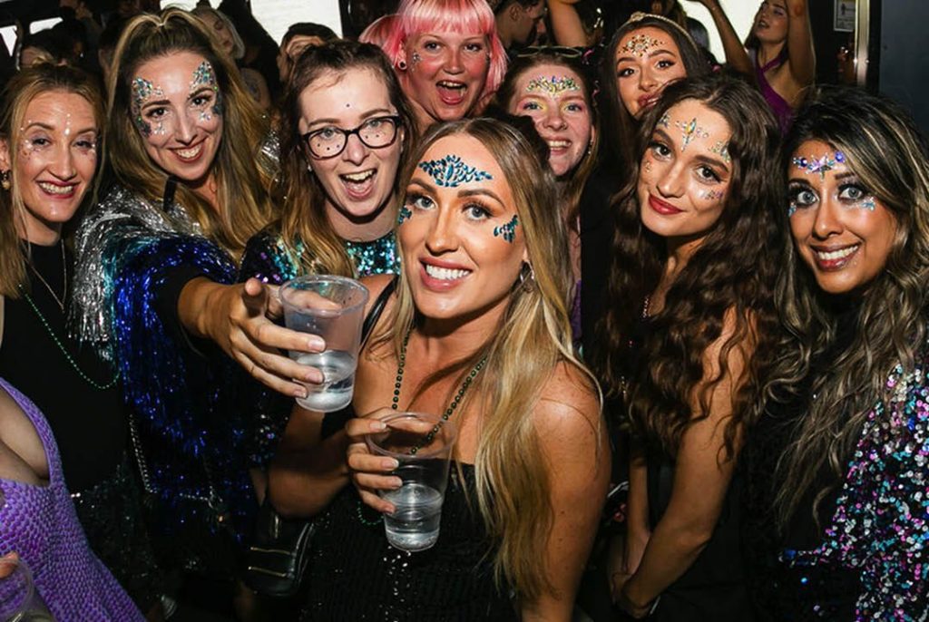Photo of a group of women wearing sparkly outfits and glitter make up at Glitterfest